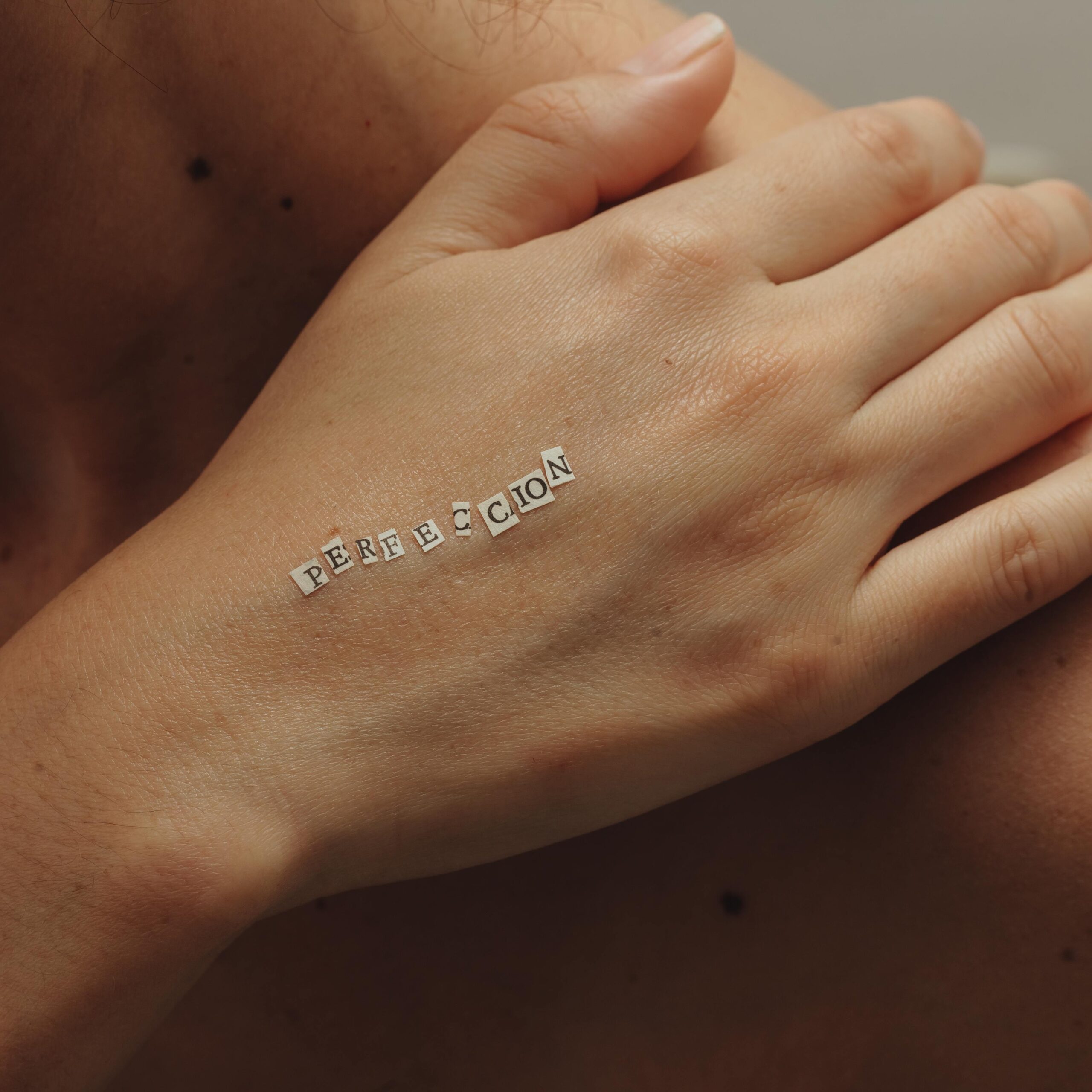 Artistic photo of a hand with 'perfección' letters, focusing on detail and texture.